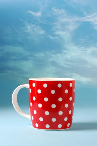 Червона чашка на красивому фоні блакитного неба з копіювальним простором — стокове фото