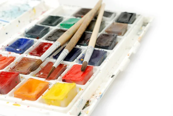 Pinturas de acuarela de uso brillante en caja y pinceles aislados sobre un fondo blanco. Macro tiro . — Foto de Stock