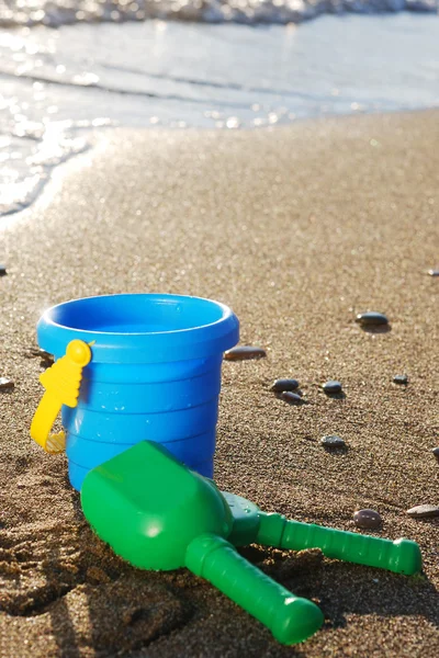 Детские пляжные игрушки, ведро и лопата, на песке у моря — стоковое фото