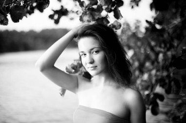 Genç, çekici, ince esmer ve mutlu bir kadının yaz yeşillikleri ve banliyö gölündeki siyah beyaz portresi.