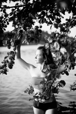 Genç, çekici, ince esmer ve mutlu bir kadının yaz yeşillikleri ve banliyö gölündeki siyah beyaz portresi.