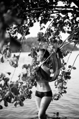 Genç, çekici, ince esmer ve mutlu bir kadının yaz yeşillikleri ve banliyö gölündeki siyah beyaz portresi.