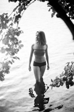 Genç, çekici, ince esmer ve mutlu bir kadının yaz yeşillikleri ve banliyö gölündeki siyah beyaz portresi.