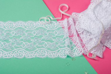 Siyah yumuşak kurdeleli beyaz bantlar, mobilyalı dantel kumaş, aksesuarlar, bantlar, pembe ve yeşil arka planda yüzükler. Elastik malzeme. Atıcı ve nakış dükkanı için kullanılıyor.