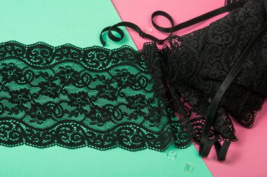 Siyah narin kurdeleli siyah bantlar, mobilyalı dantel kumaş, aksesuarlar, bantlar, pembe ve yeşil arka planda yüzükler. Elastik malzeme. Atıcı ve nakış dükkanı için kullanılıyor.