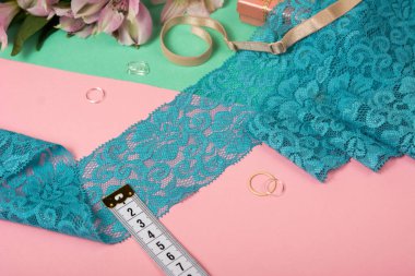 Zarif mavi kurdele, mobilya ve çiçekli dantel kumaş, aksesuarlar, bantlar, pembe ve yeşil arka planda yüzükler. Elastik malzeme. Atıcı ve nakış dükkanı için kullanılıyor.