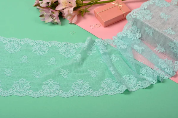 Zarif mavi kurdele, mobilya ve çiçekli dantel kumaş, aksesuarlar, bantlar, pembe ve yeşil arka planda yüzükler. Elastik malzeme. Atıcı ve nakış dükkanı için kullanılıyor.