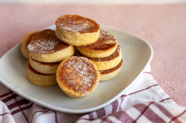 Ev yapımı Pile Pluffy Sufle Pancake, badem, hindistan cevizi, soya unu. Tatlı pudrayla yakın çekim. Beyaz tabakta, pembe grunge betonda ketojenik yiyecekler. Tekstil pamuk havlu. Japon Biçimli Tatlı.