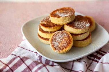 Ev yapımı Pile Pluffy Sufle Pancake, badem, hindistan cevizi, soya unu. Tatlı pudrayla yakın çekim. Beyaz tabakta, pembe grunge betonda ketojenik yiyecekler. Tekstil pamuk havlu. Japon Biçimli Tatlı.