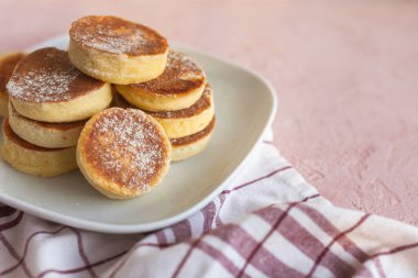 Ev yapımı Pile Pluffy Sufle Pancake, badem, hindistan cevizi, soya unu. Tatlı pudrayla yakın çekim. Beyaz tabakta, pembe grunge betonda ketojenik yiyecekler. Tekstil pamuk havlu. Japon Biçimli Tatlı.