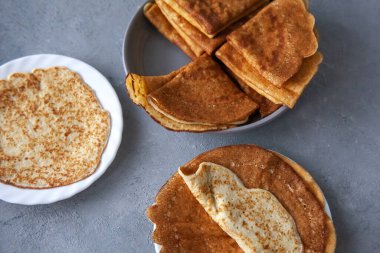 Lezzetli kızarmış ince krepler beyaz tabakta gri beton arka planda, karnaval shrove günü, soya karbonhidratsız protein ketojenik fırın ürünleri.