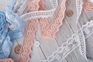 Klasik pembe beyaz ve mavi pamuk bantlar ve bej ahşap arka planda yuvarlak düğmeler.