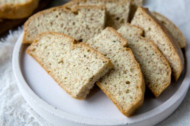 Ev yapımı badem düşük karbonhidratlı ketojenik ekmek kepek ve lifli tabakta, tahta kesme tahtası bıçakla, bej rengi beton zeminde açık keten peçete. Glutenfree vejetaryen gıda konsepti.
