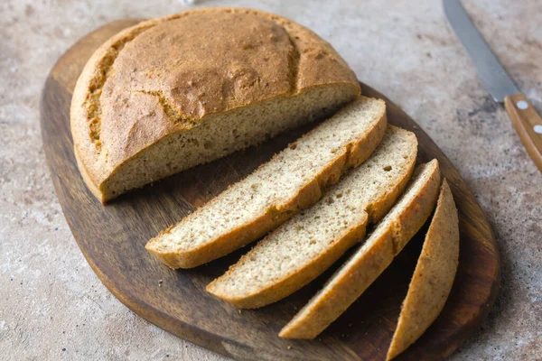Ev yapımı badem düşük karbonhidratlı ketojenik ekmek kepek ve lifli tabakta, tahta kesme tahtası bıçakla, bej rengi beton zeminde açık keten peçete. Glutenfree vejetaryen gıda konsepti.