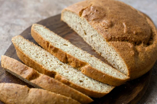 Ev yapımı badem düşük karbonhidratlı ketojenik ekmek kepek ve lifli tabakta, tahta kesme tahtası bıçakla, bej rengi beton zeminde açık keten peçete. Glutenfree vejetaryen gıda konsepti.