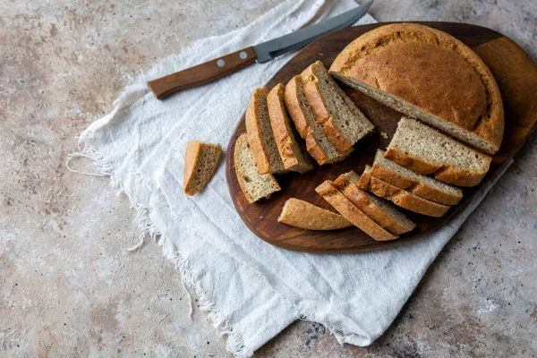 Ev yapımı badem düşük karbonhidratlı ketojenik ekmek kepek ve lifli tabakta, tahta kesme tahtası bıçakla, bej rengi beton zeminde açık keten peçete. Glutenfree vejetaryen gıda konsepti.