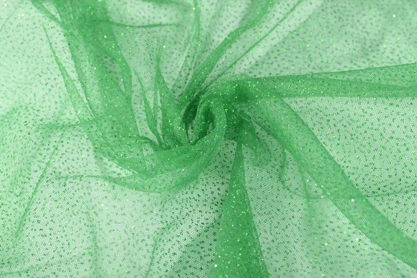 Lightweight green Crumpled beautifully draped lace festive tulle fabric with sparkles. texture of wedding clothes, veil, dress, skirt. Use for sew fashion industry with copy space. Close up soft focus
