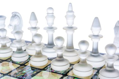 Şeffaf farklı cam satranç taşları beyaz inci tahtanın üzerinde duruyor. Parıltılı ve mat şekilli. oyun karşılaşma konsepti.