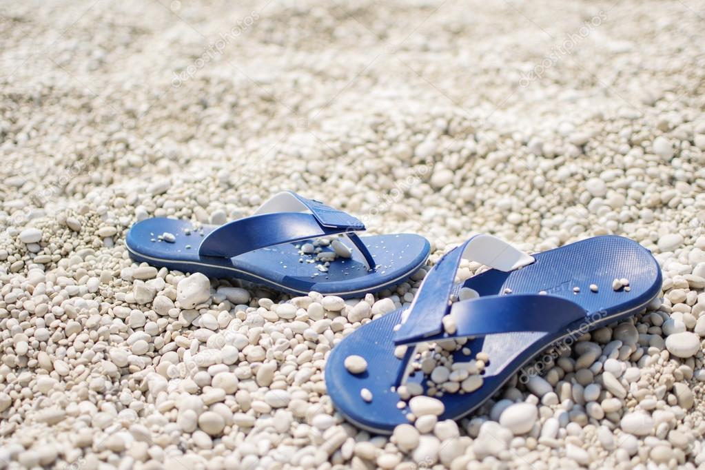 blue rubber flip flops on white sand