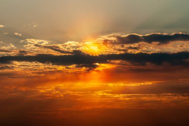 Güzel koyu turuncu gökyüzü ve güneş ışığı gün batımında bulutların arasında parlıyor.
