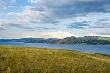 Büyük Sibirya nehri Yenisei 'nin üzerinde akşam batımı. Arka planda dağ sırası olan güzel bir manzara. Seçici odak.