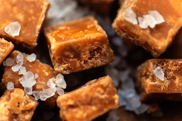 Salted caramel pieces and sea salt close up. Butter caramel cand — Stock Photo, Image