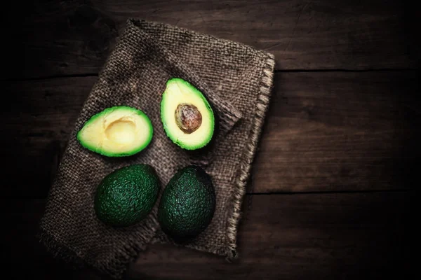 Gehalveerde avocado op rustieke tafel. — Stockfoto