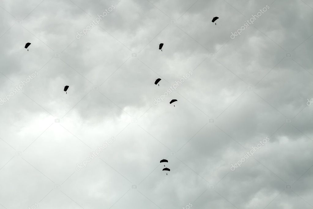 Parachutists siluets in sky