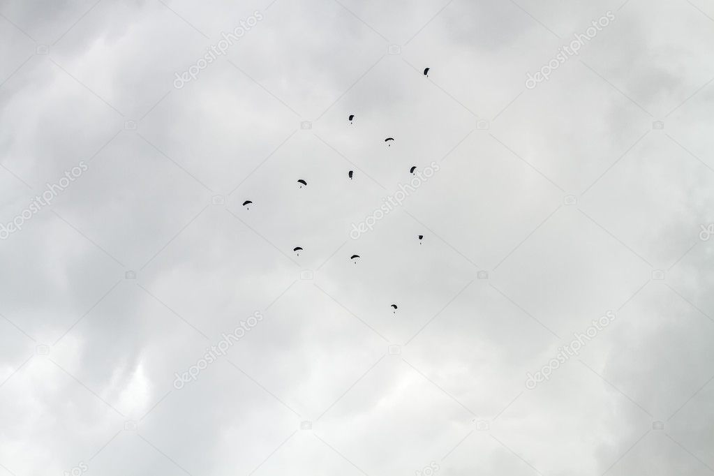 Many parachutists descends cloudy sky