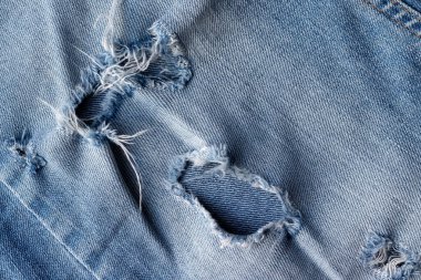 Mavi yırtık kot kumaş kumaş. Delik ve dikiş arkaplan ile sıkıntılı kot