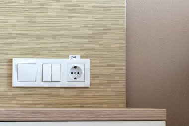 Beyaz Avrupa elektrik prizi grubu ve otel odasındaki bir duvarda düğmeler