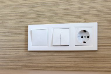 Beyaz Avrupa elektrik prizi grubu ve otel odasındaki bir duvarda düğmeler