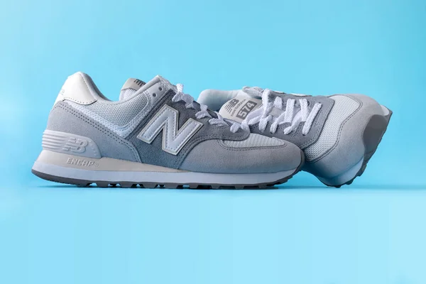 New Balance 574 hellgraue Turnschuhe auf blauem Hintergrund. Wildleder- und Mesh-Walking, lässige Sportschuhe in Nahaufnahme. Illustratives Leitartikel-Foto — Stockfoto