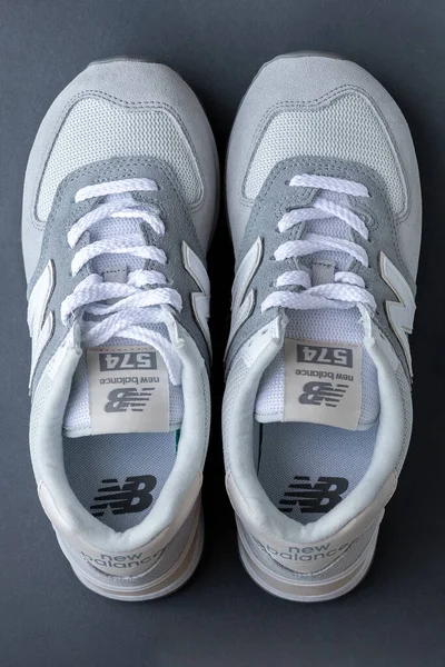 Zapatillas New Balance 574 gris claro sobre fondo gris. Gamuza y malla caminando, casual sport shoes de primer plano. Fotografía vertical editorial ilustrativa —  Fotos de Stock
