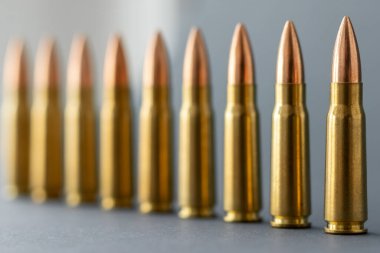 Gri arka plandaki kurşunlar. Kalaşnikov taarruz tüfeği için 7.62 kalibrelik fişekler. Önplanda seçmeli odak