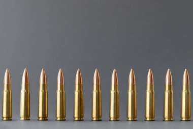 Gri arka plandaki kurşunlar. Kalaşnikov taarruz tüfeği için 7.62 kalibrelik fişekler. Kopya alanı ile yakın plan.