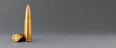 Gri arka planda iki kurşun. Kalaşnikov taarruz tüfeği için 7.62 kalibrelik fişekler. Fotokopi alanı olan geniş pankartı kapatın.