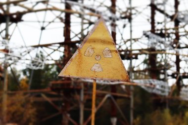 Old yellow radiation sign against the Duga Radar antenna complex. Chernobyl Exclusion Zone, Ukraine. Tilt-shift effect clipart
