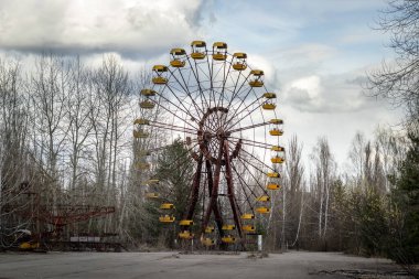 Pripyat, Çernobil Yasak Bölgesi 'ndeki eğlence parkında dramatik gökyüzüne karşı eski terk edilmiş paslı metal radyoaktif sarı dönme dolap.