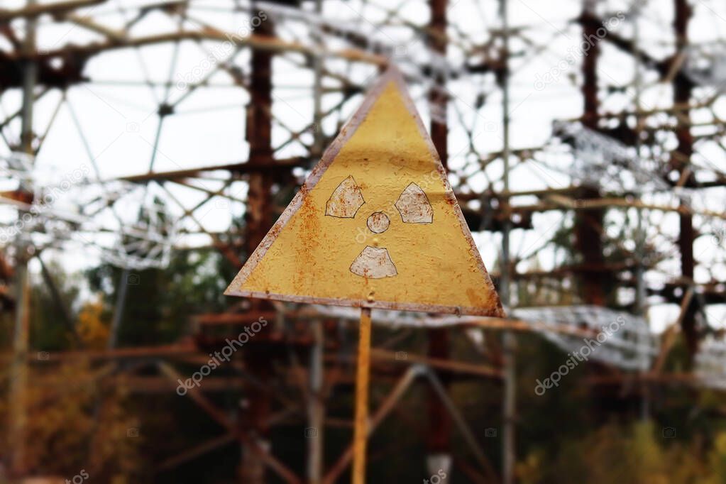 Old yellow radiation sign against the Duga Radar antenna complex. Chernobyl Exclusion Zone, Ukraine. Tilt-shift effect