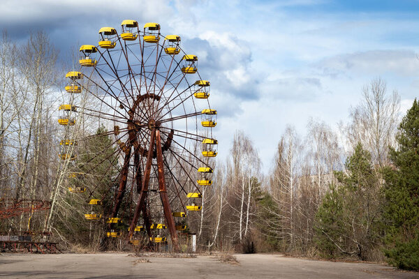 Old abandoned rusty metal radioactive yellow ferris wheel against dramatic sky in amusement park in ghost town Pripyat, Chernobyl Exclusion Zone