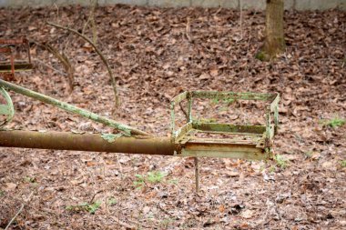 Pripyat, Çernobil Yasaklama Bölgesi, Ukrayna 'daki ağaçlar arasında terk edilmiş oyun parkında eski paslı metal atlıkarınca salıncak.