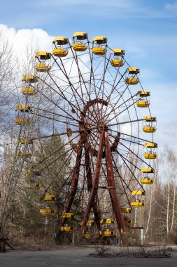 Pripyat, Çernobil Yasak Bölgesi 'ndeki eğlence parkında dramatik gökyüzüne karşı eski terk edilmiş paslı metal radyoaktif sarı dönme dolap.