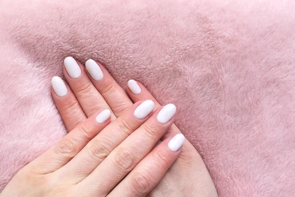 Hände mit weißen Nägeln auf rosa Textilhintergrund — Stockfoto