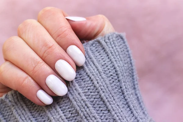 Hand med vita naglar på rosa textil bakgrund — Stockfoto