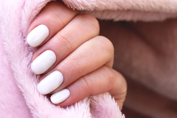 Hand mit weißen Nägeln auf rosa Textilhintergrund — Stockfoto