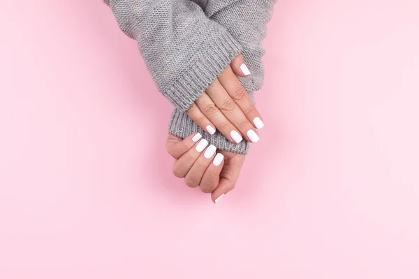 Hände im Pullover mit weißen Nägeln auf rosa Hintergrund — Stockfoto