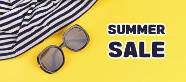 Kahverengi güneş gözlüğü ve denizci beyaz çizgili kumaş. Parlak sarı arka planda. Yazın indirimli.