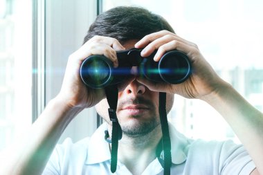 Yakışıklı sakallı adam, parlak yeşil ve mavi ışıklı dürbünle dürbünlere bakıyor.