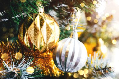 Güzel altın ve gümüş toplar, bulanık ışıklarla süslenmiş Noel ağacında. Seçici odaklanma. Yılbaşı arifesi için süslemeli tatil kartı.